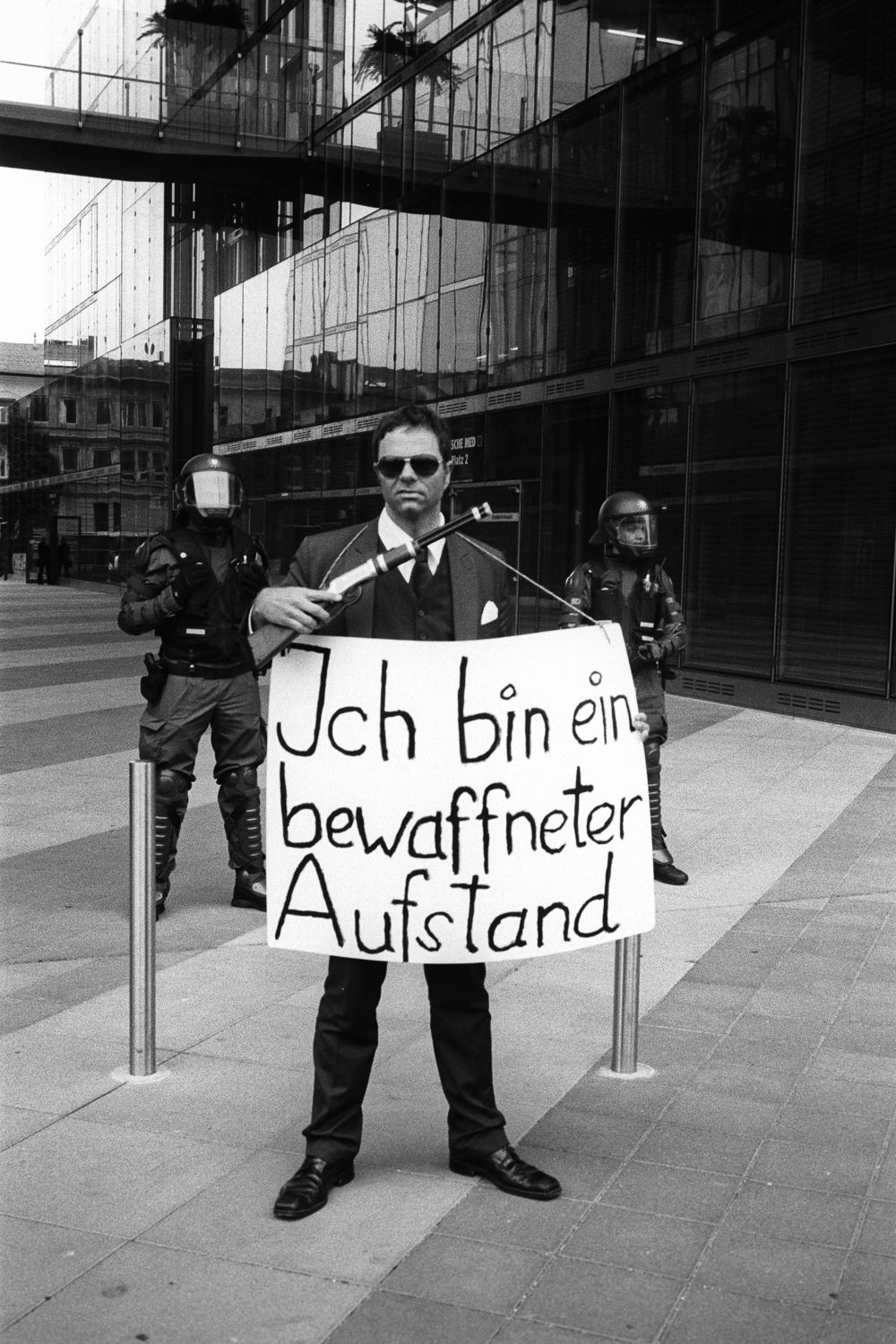 A protester holding a sign "Ich bin ein bewaffneter Aufstand [I am an armed riot]", Rostock, June 2007