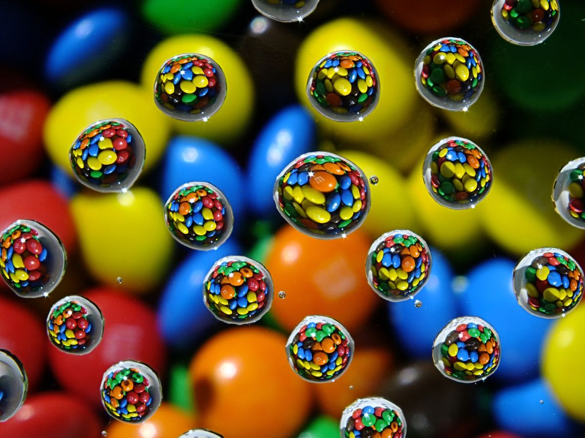 Water droplets on a piece of glass over a bowel of M&Ms  