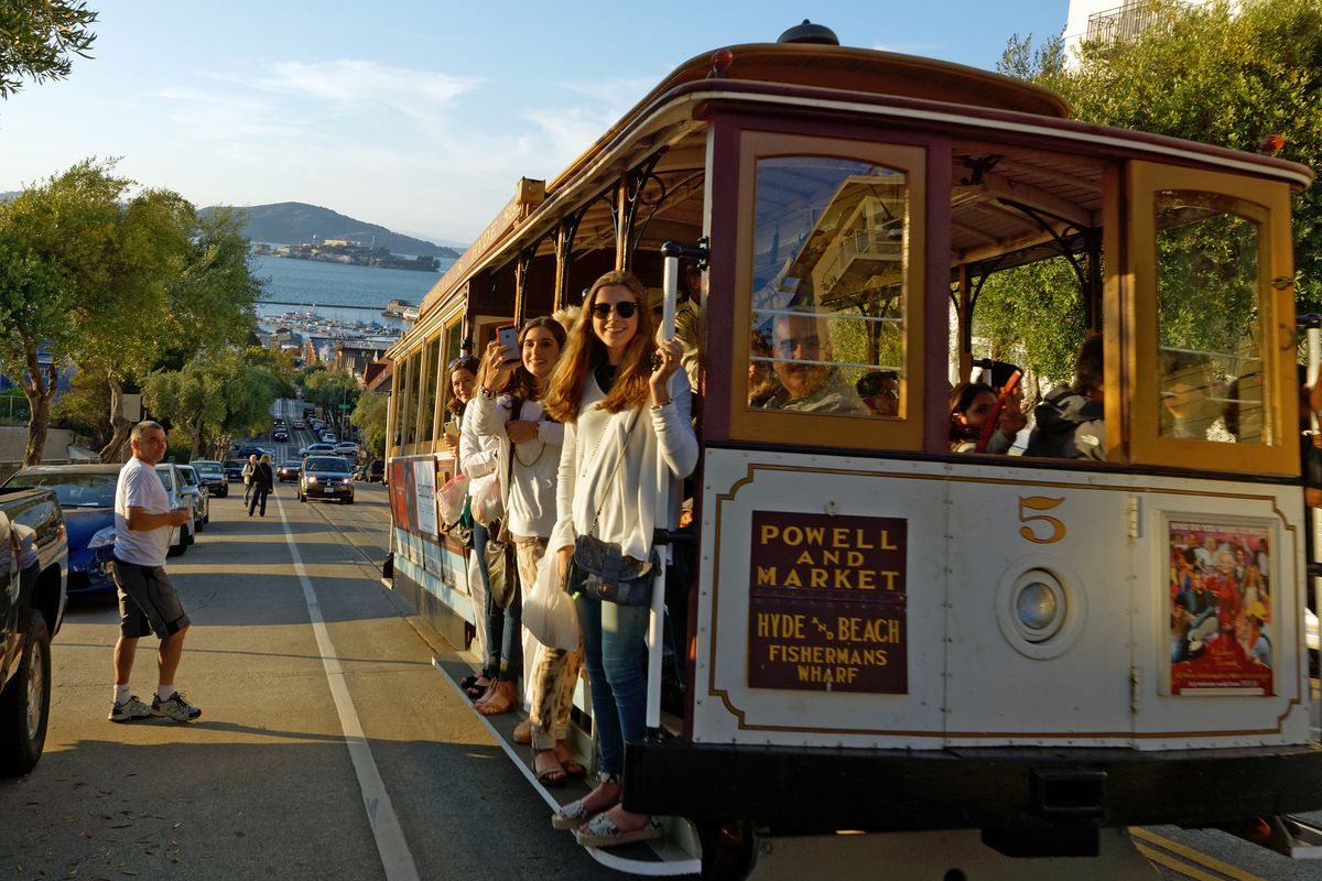 Die Cable Cars sind bei Touristen ein beliebtes Verkehrsmittel und ein Erkennungszeichen dafür dass man sich in San Francisco befindet. In Hintergrund ist die Bucht von San Francisco mit dem ehemaligem Gefängnis Alcatraz zuerkennen. Location : San Francisco in US-Bundesstaat Kalifornien in Jahr 2015